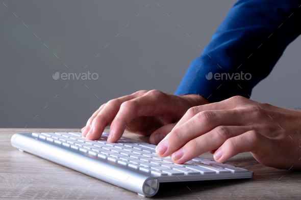Close up of caucasian businessman typing on keyboard, isolated on grey background - Stock Photo - Images