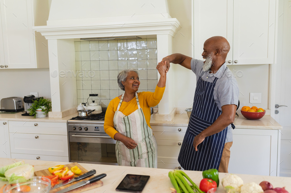 Senior african american couple dancing together in kitchen smiling ...