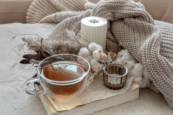 A cozy composition with candles, dried flowers in a vase and a knitted  element. Stock Photo by puhimec