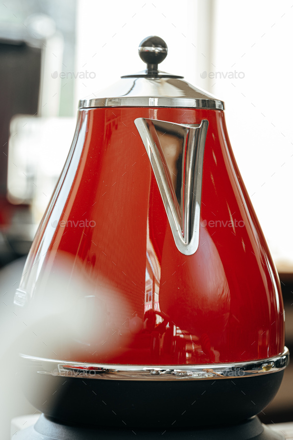 Red kettle on kitchen table close up
