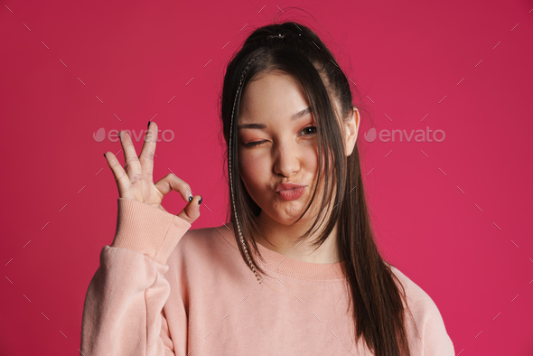 Asian brunette woman winking and gesturing ok sign