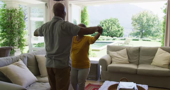 African american senior couple hugging each other in the living room at home alt