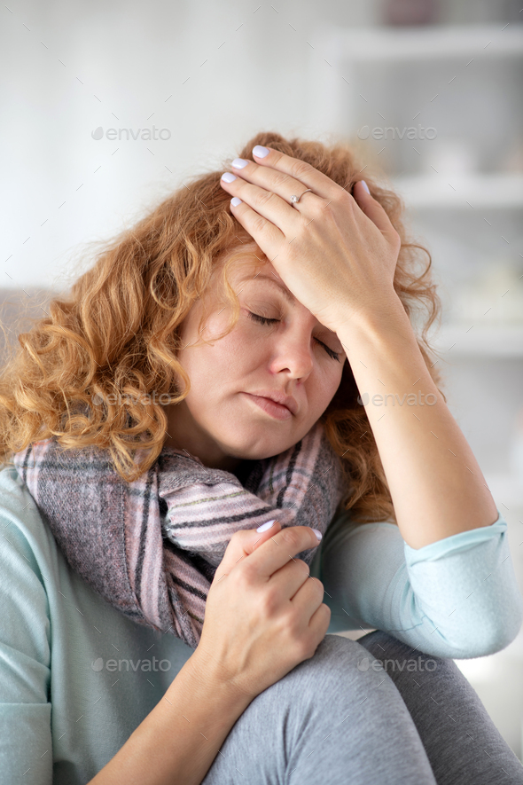 Curly woman wearing checked scarf suffering from fever