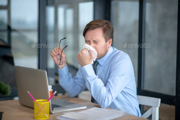 Man sitting in front of laptop and sneezing while having flu Stock ...