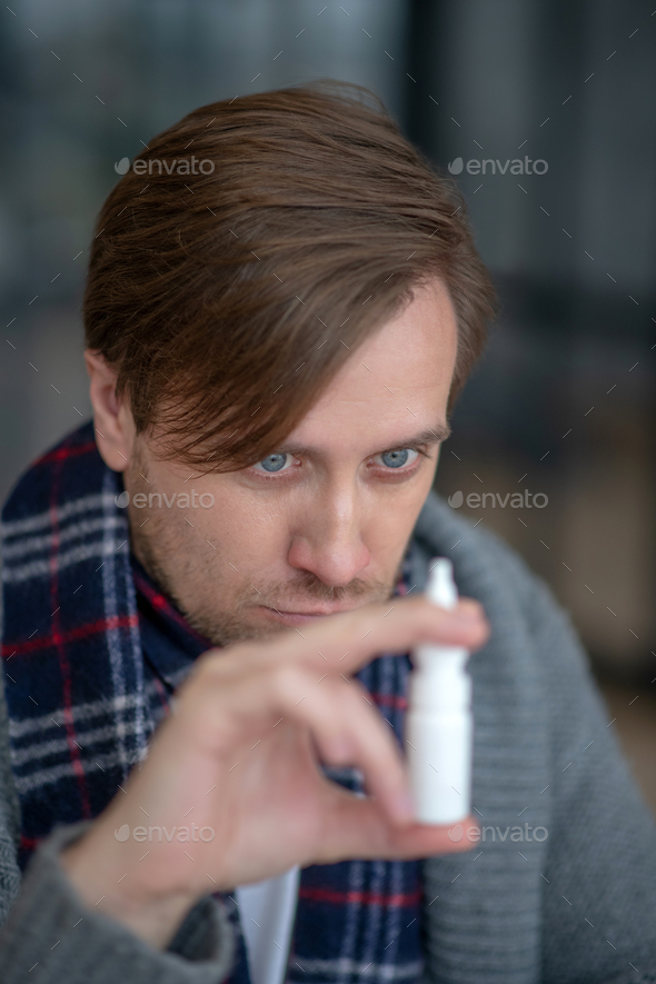 Man looking at nasal spray while having stuffy nose Stock Photo by