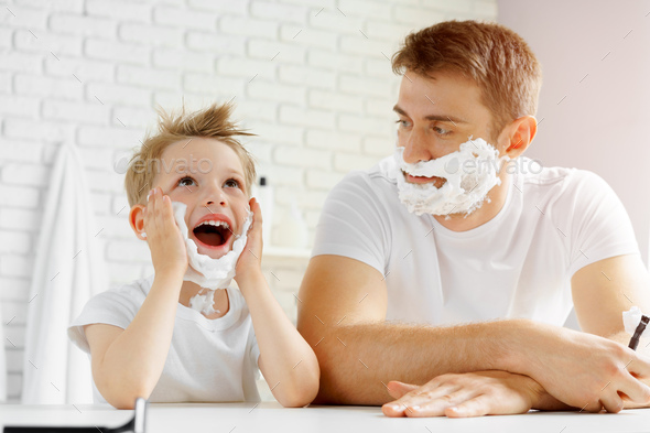 Father and little son having fun with shaving foam