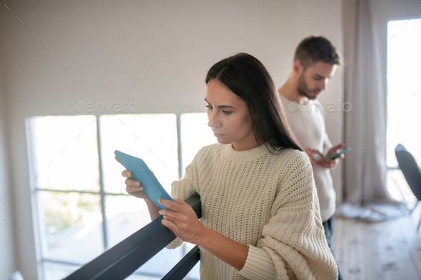 Wife feeling suspicious while reading messages on tablet - Stock Photo - Images