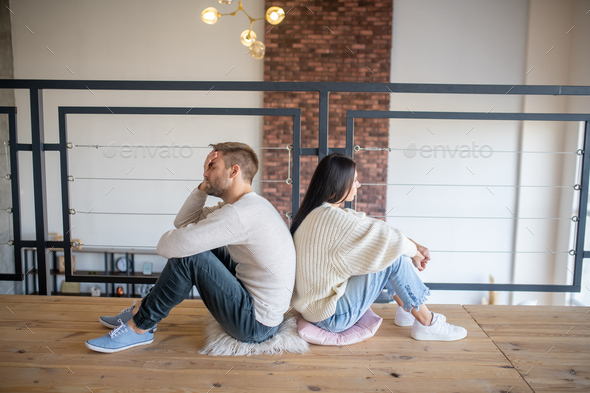 Husband and wife sitting back to back after emotional talk