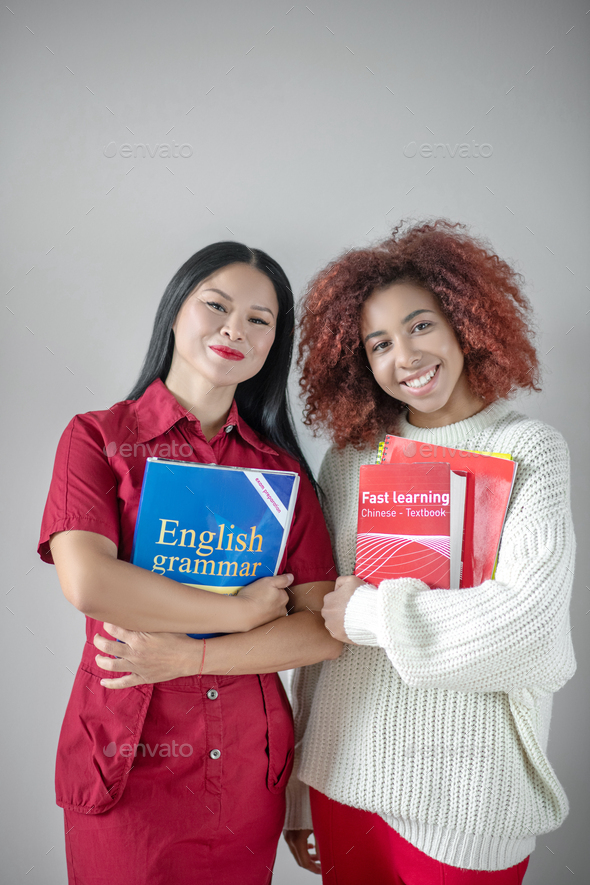 Beaming female friends studying English grammar together
