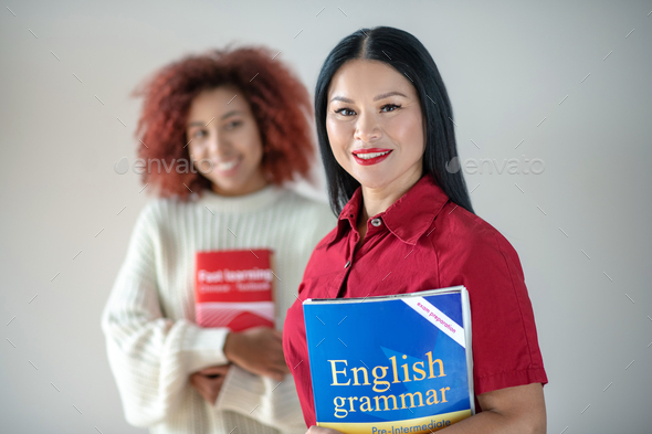 Woman holding English grammar book while studying languages