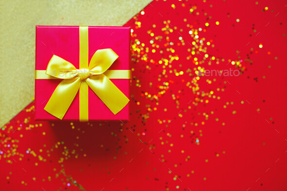 gift box with bow on red-gold background Stock Photo by Aleksandra_Iarosh