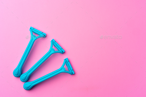 Female disposable razors on pink background top view