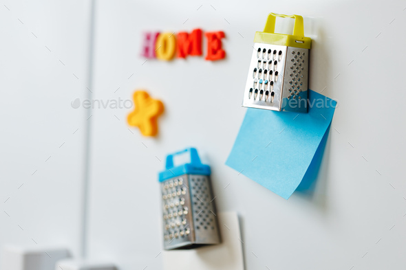 Sheets of paper and magnets on fridge door in kitchen