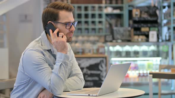 Man with Laptop Talking on Phone alt