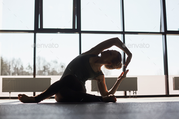 Silhouette of a girl doing yoga against the background of panoramic Windows  in a modern yoga Studio Stock Photo by sviatlankayanka