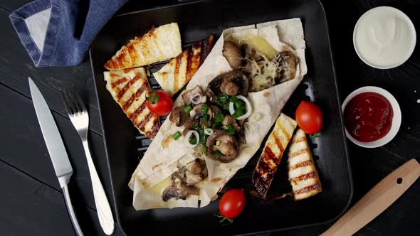 Vegetarian Pita Bread with Mushrooms and Cheese Rotates on a Wooden Table in a Square Skillet Grill alt