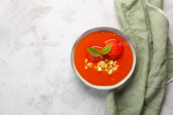 Plate with cold soup in the form of mashed gazpacho in a plate on a gray background