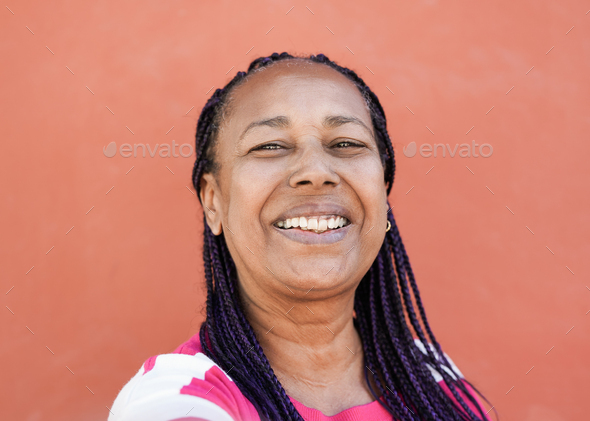 Cool elderly african woman with braids taking a selfie while smiling in camera