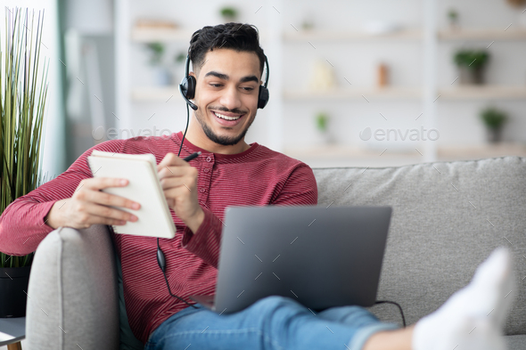 Cheerful middle-eastern man having online class while staying home