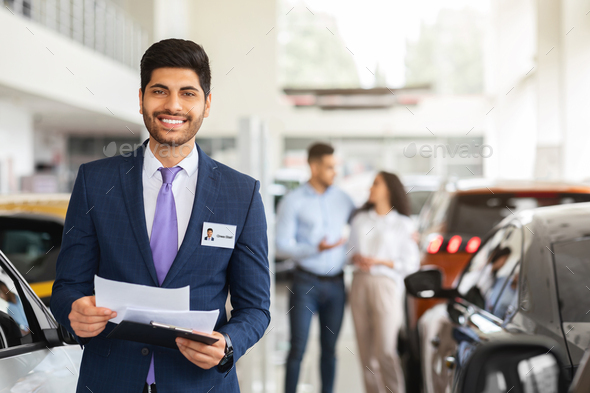 Charismatic arab man sales assistant posing over auto showroom