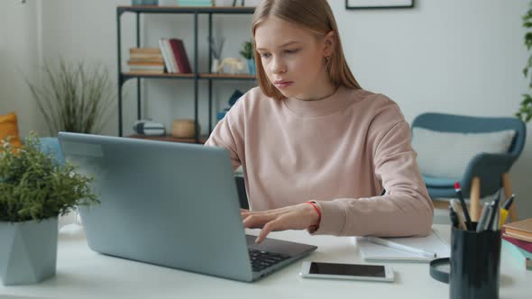 Tired Teenager Using Laptop Typing Then Touching Head Feeling Headache Studying Alone in Apartment alt