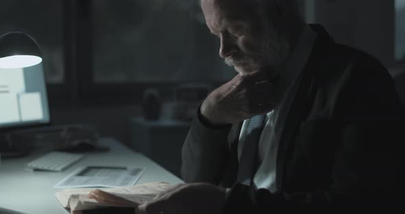 Businessman checking stock market news on the newspaper at night in the office