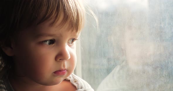 Portrait of a Lonely Upset Toddler Looking Out the Window