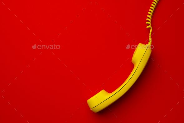 Yellow landline phone on red background top view