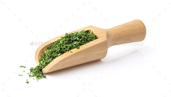 Dried parsley in wood scoop on a white background