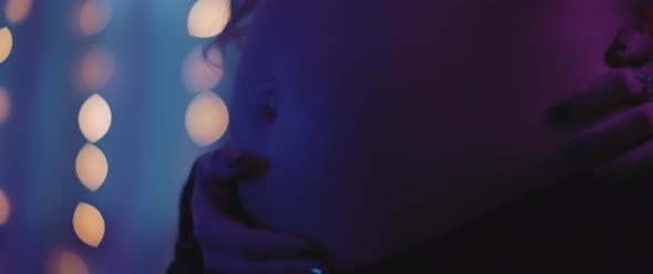 Close up of a pregnant woman's belly, mother's holding holding her hands on her stomach. alt