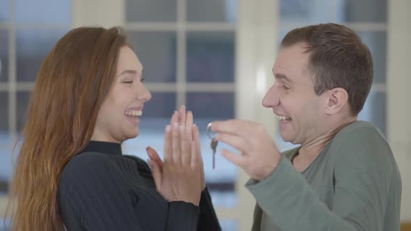 Portrait of a Happy Married Couple Showing the Keys of a Purchased New House or Apartment alt