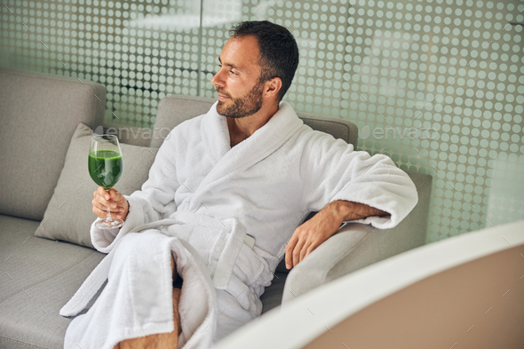 Handsome young man drinking smoothie in spa salon Stock Photo by svitlanah