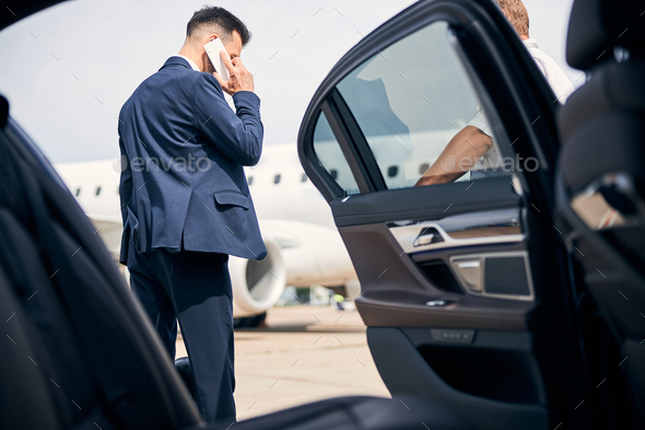 Man in a suit having a phonecall by the taxi