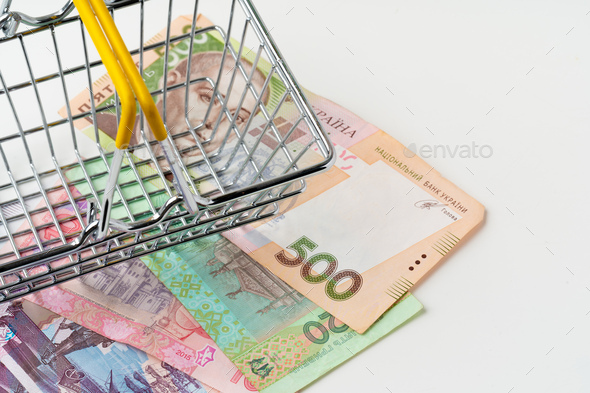 Toy shopping cart with Ukrainian hryvnia money. Purchasing power and living wage concept - Stock Photo - Images