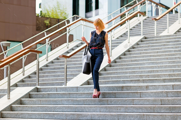 Elegant fashionable woman descending exterior steps in town - Stock Photo - Images
