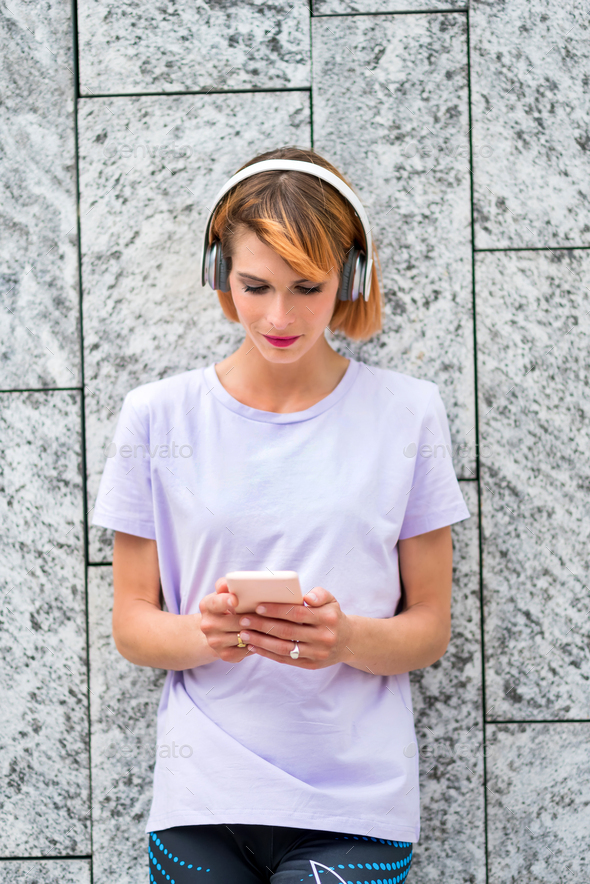 Cute attractive mature woman listening to music on mobile phone - Stock Photo - Images