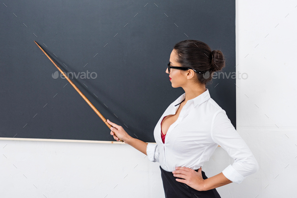 young beautiful teacher pointing at chalkboard