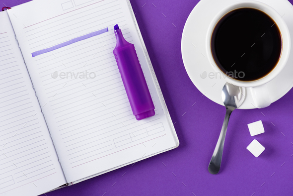 top view of workspace with opened notebook and cup of coffee