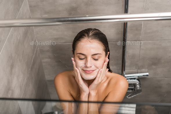 Overhead view of Girl cleaning face with facial wash gel in the shower