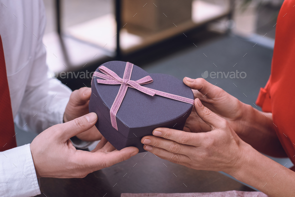 cropped image of husband presenting gift to wife on valentines day