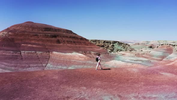 Cinematic Aerial Shot of Woman Walking By Red Sandstone Hills Traveler Backpack alt