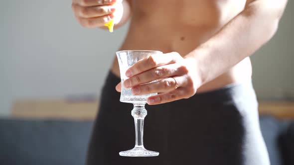 Close Up of Young Fit Slim Woman Preparing Water with Lemon Juice alt