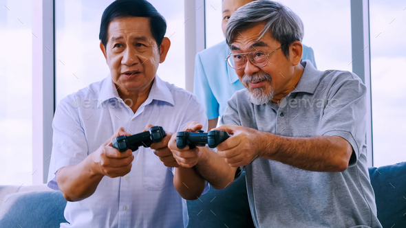Group of senior friends playing video game together in a retirement home - Stock Photo - Images