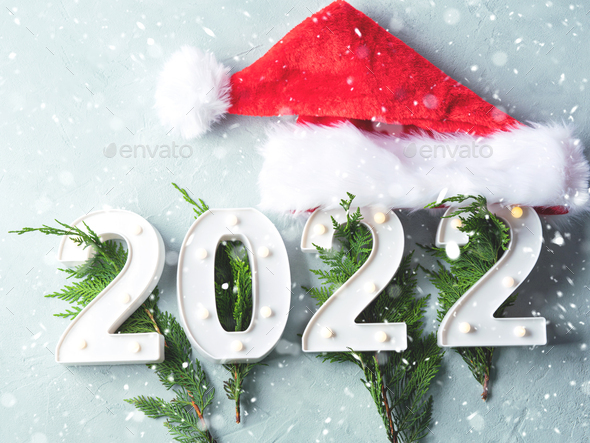 New year 2022 numbers with fir tree branches and santa cap on gray  background. Holiday greeting card Stock Photo by tenkende
