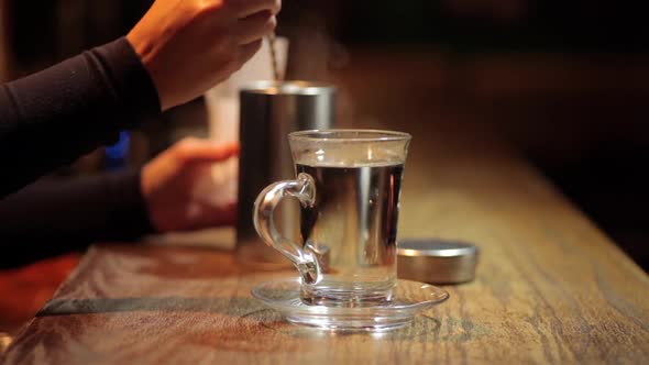 Woman placing a glass of hot water on a counter