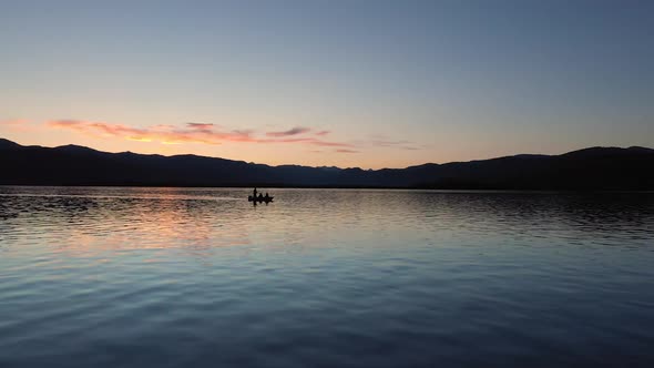 Flying low over a lake at dusk past small fishing boat alt