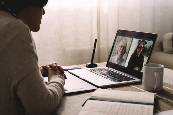 Young woman having video call with her colleagues using computer app - Multi generational business - Stock Photo - Images