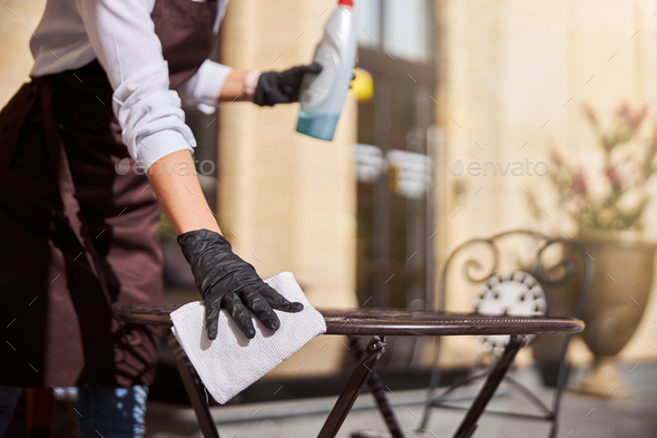 Female in gloves preparing cafe for open the guest