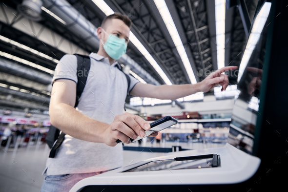 Man using self service check-in machine at airport - Stock Photo - Images