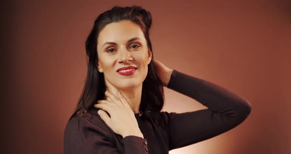 Beautiful Woman Poses in Studio on Brown Background